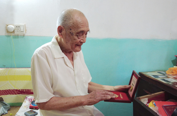 4、王成国抚摸着奖章（谭剑 摄）.jpg